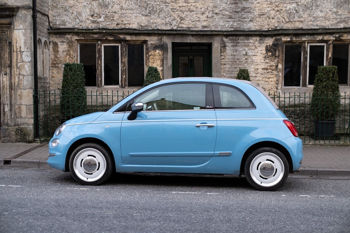 Blue car parked beside a stone building