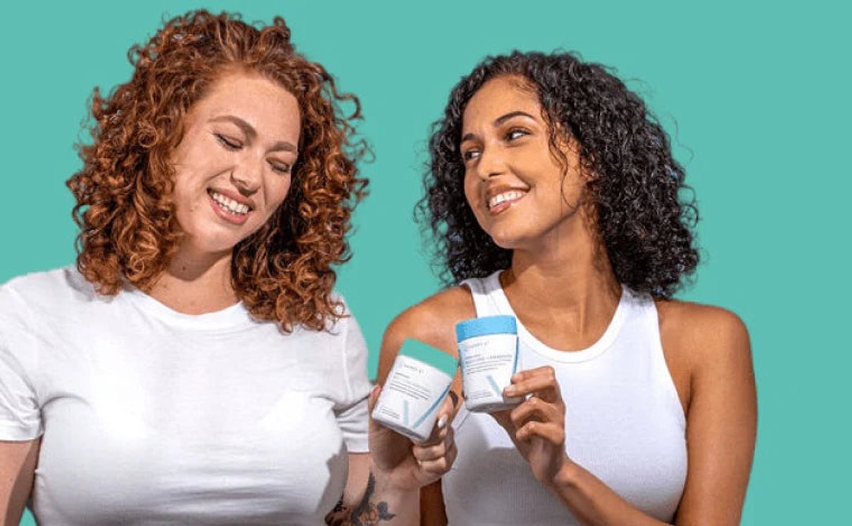 Two women holding Happy V wellness products