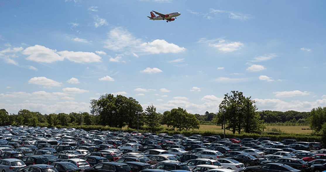Airport car park with a plane in the background