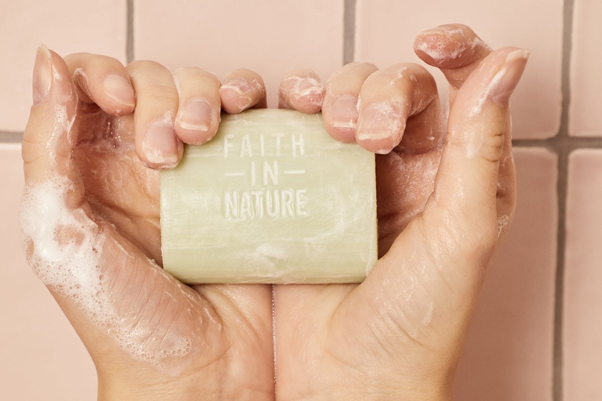 Hands lathering a Faith In Nature soap bar