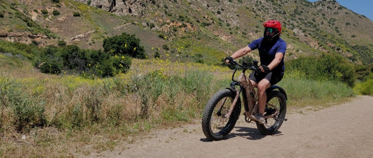 A rider on a Puckipuppy electric bike along a dry outdoor trail